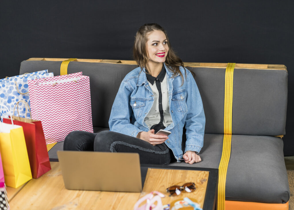 cheerful woman sitting sofa with colorful shopping bags home