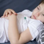 front view sick child sitting bed scaled.jpg