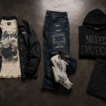 Oversized streetwear outfit with distressed denim, heavyweight hoodie, varsity jacket, and sneakers in urban setting
