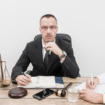 Criminal defense attorney meeting with a client in a law office while reviewing legal documents and discussing a criminal case.