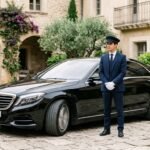 Chauffeur standing next to sedan 202607290137